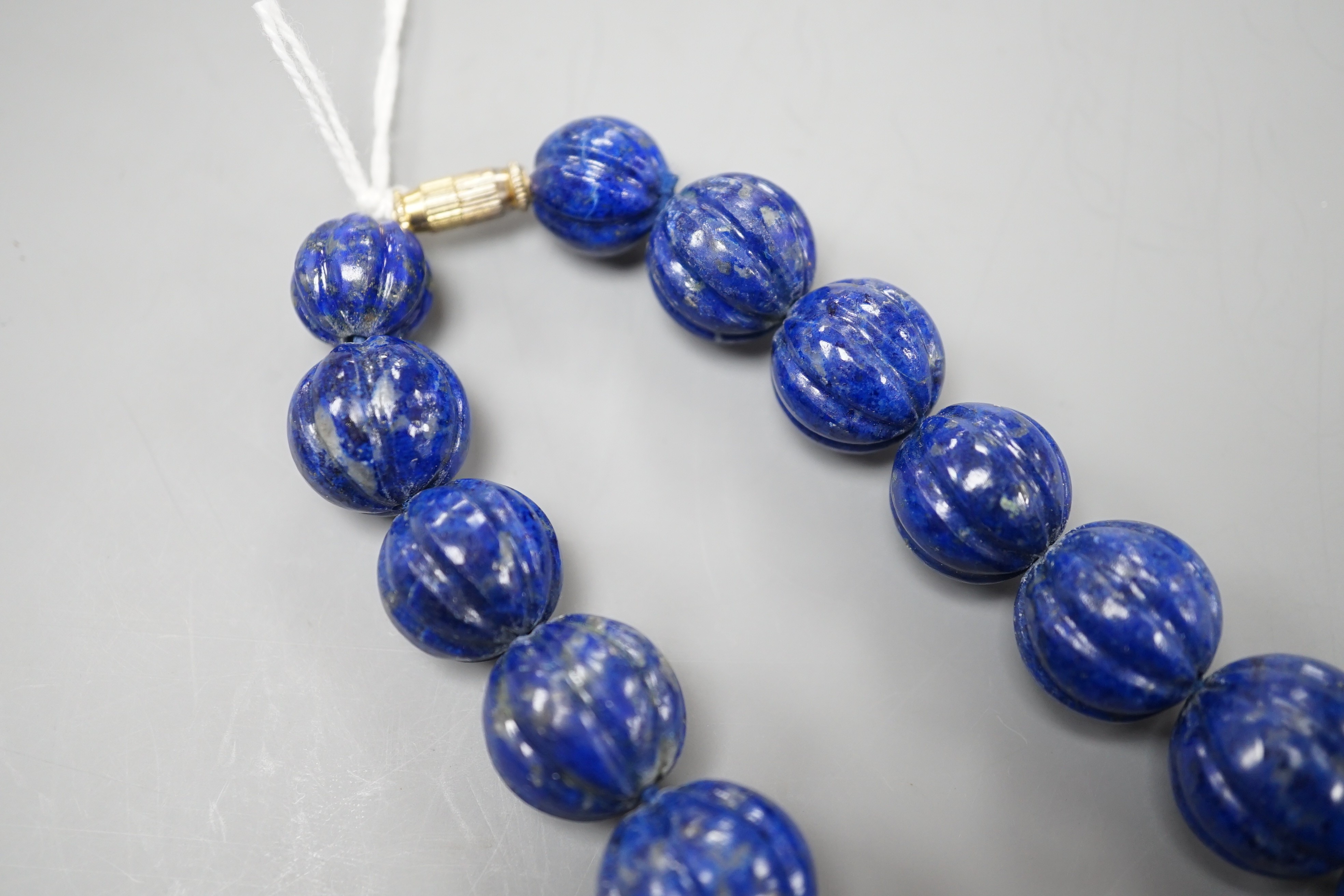 A single strand graduated fluted lapis lazuli bead necklace, 44cm